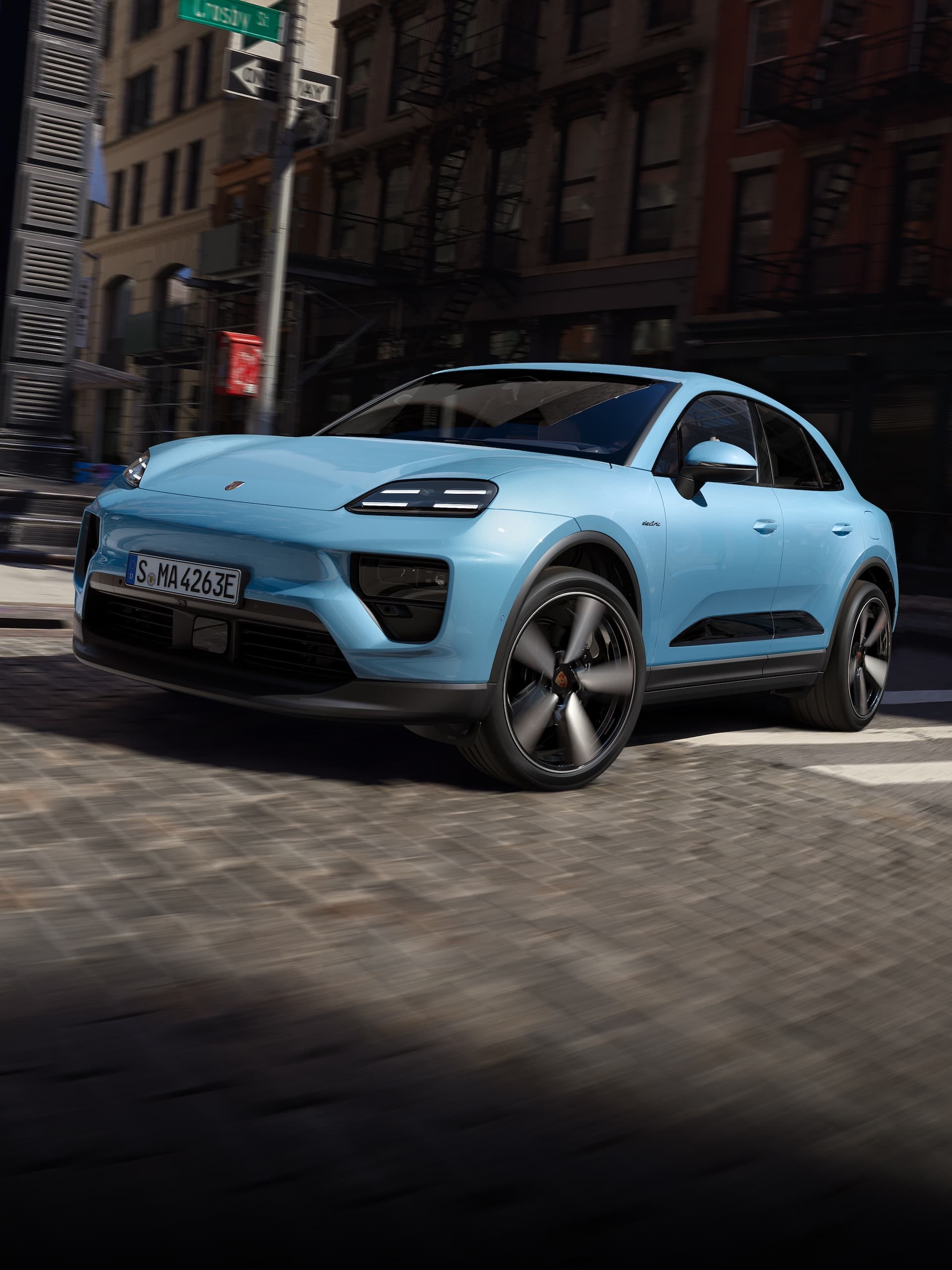 Ein Porsche vollelektrischer Macan, der in einem urbanen Szenario eine Straße hinunterfährt.
